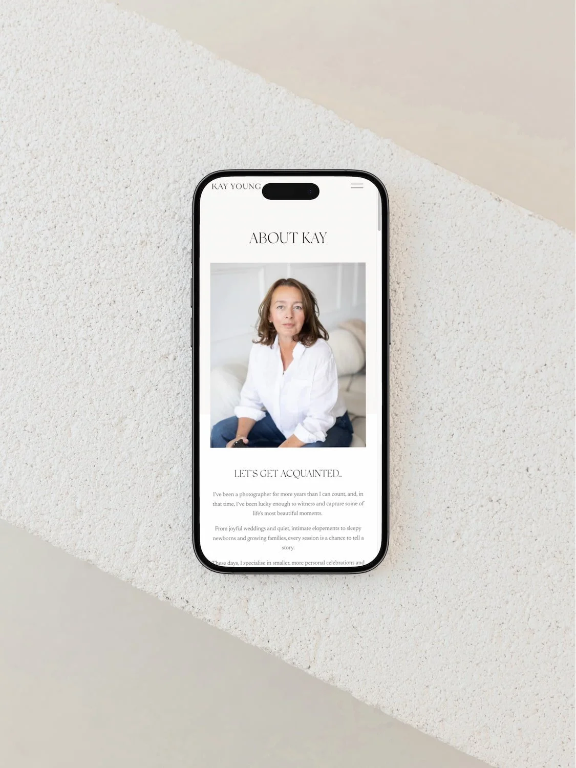 mock up of a neutral squarespace website for a photographer on a mobile phone positions on a concrete table top