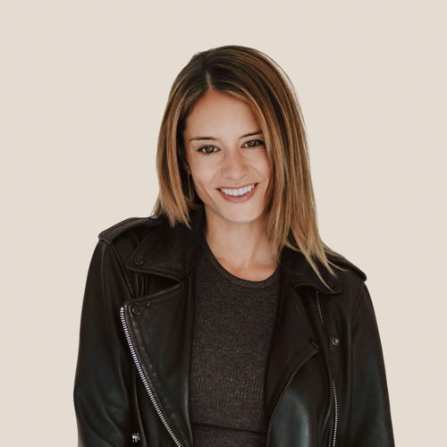 brunette woman smiling to camera against a grey backdrop