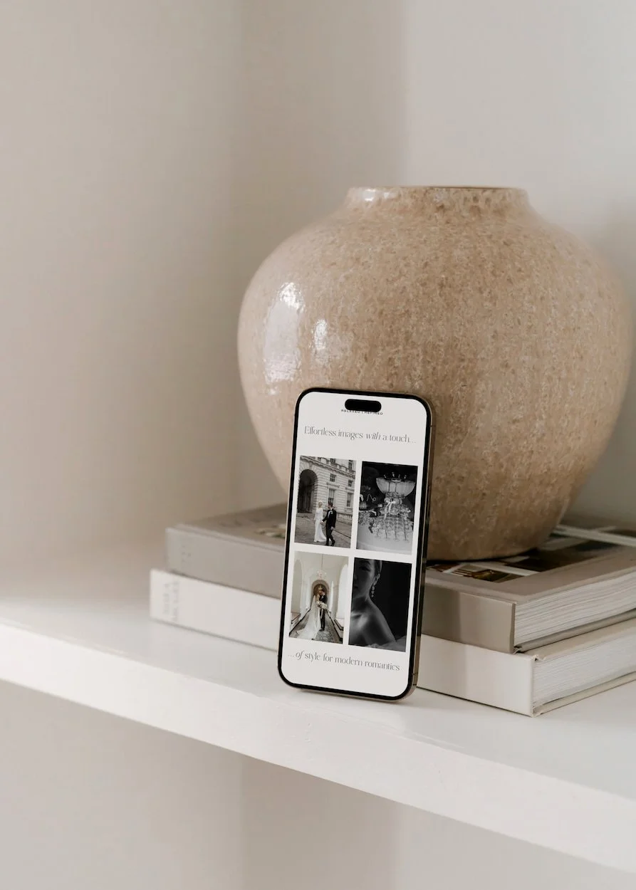 mock up of a website on a mobile phone leaning against a cream vase