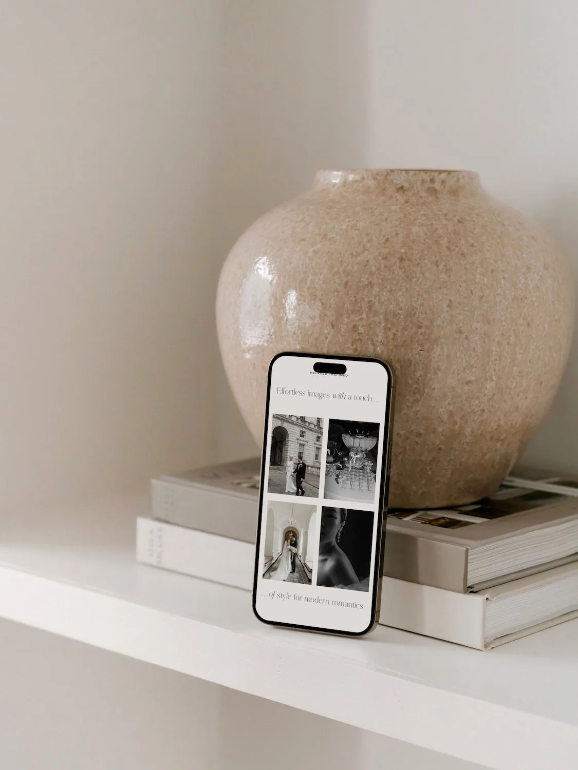 mock up of a squarespace website for a photographer on a mobile phone leaning against a beige marble vase
