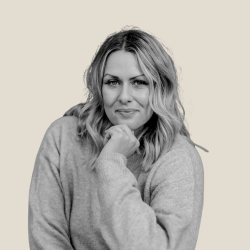 blonde woman smiling to camera against a grey backdrop