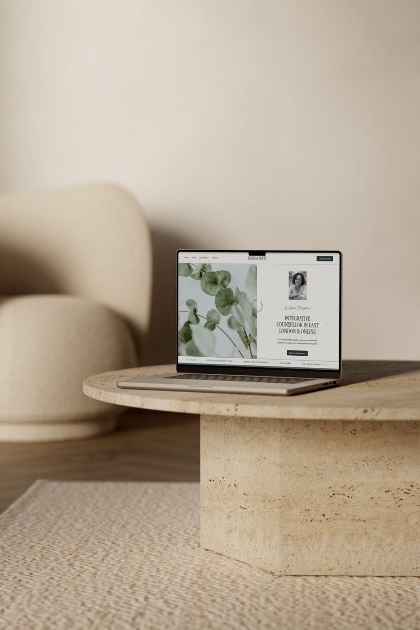 mock up of counsellors website on a laptop resting on a beige marble coffee table