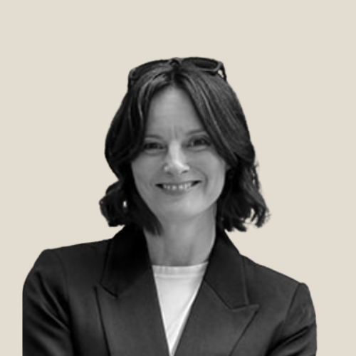female coach wearing a black blazer smiling to camera