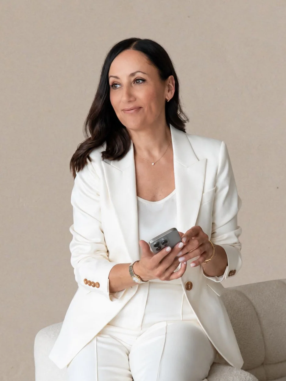 clare butler uk squarespace designer wearing a white suit sitting on a cream sofa