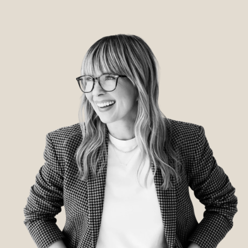 woman in glasses, dogstooth jacket and white t shirt smiling