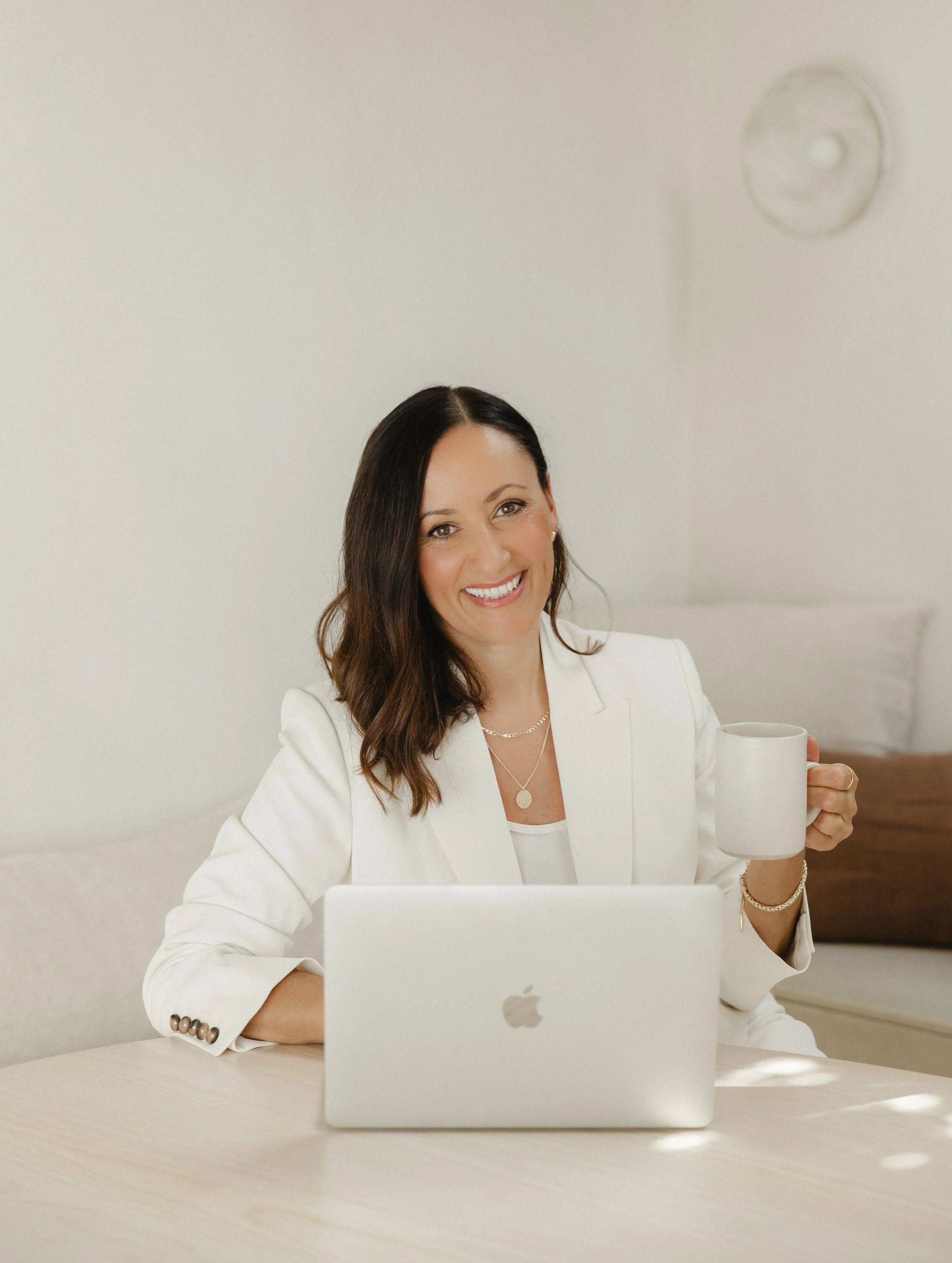 web designer sitting at a stylish light wooden desk with an open silver laptop