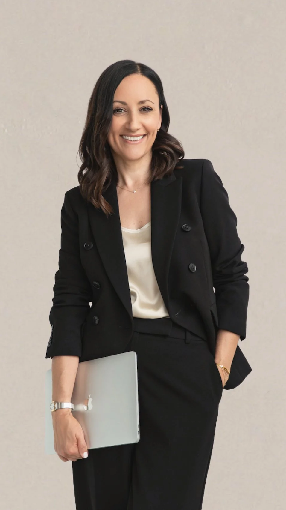 clare butler expert uk squarespace web designer wearing black suit holding a closed laptop underarm