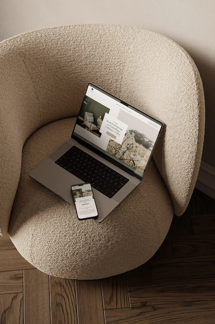 elegant mock up of a counsellors website on a laptop resting on a cream bubble armchair