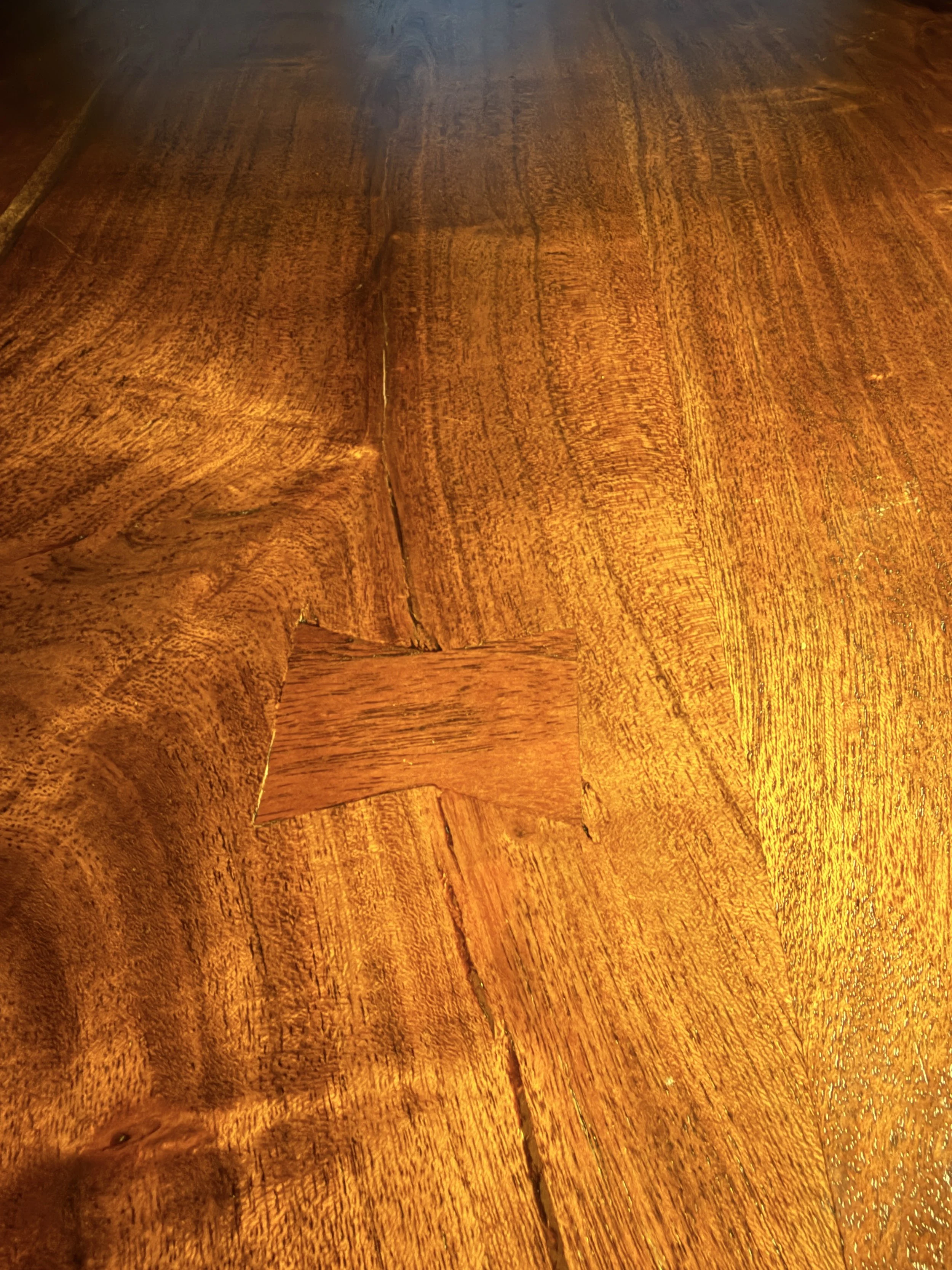 Close-up of a polished wooden surface with visible grains and a small rectangular section of wood patch.
