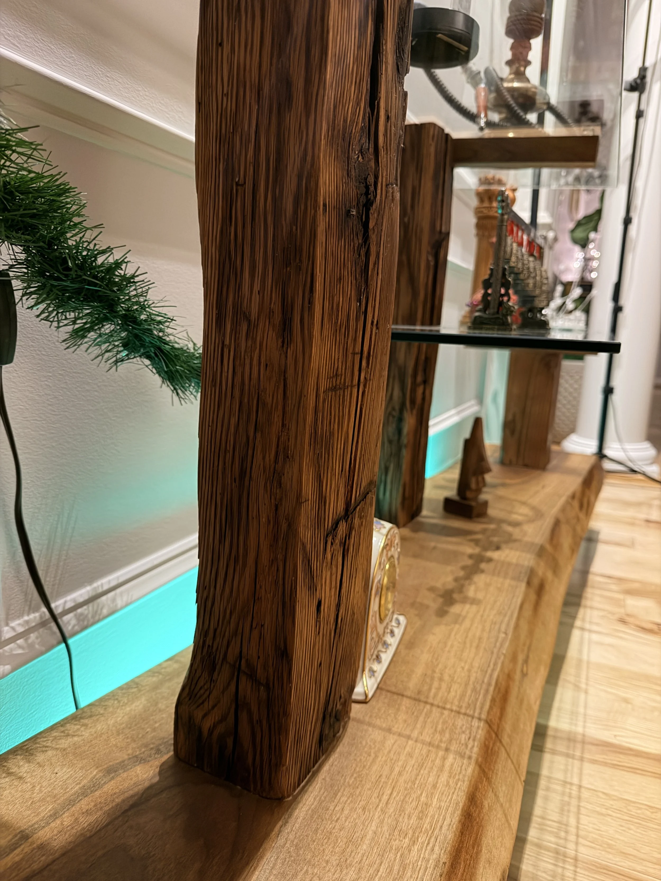 Close-up of a distressed wooden beam on a wooden shelf or piece of furniture, with other decorative items and objects in the background.