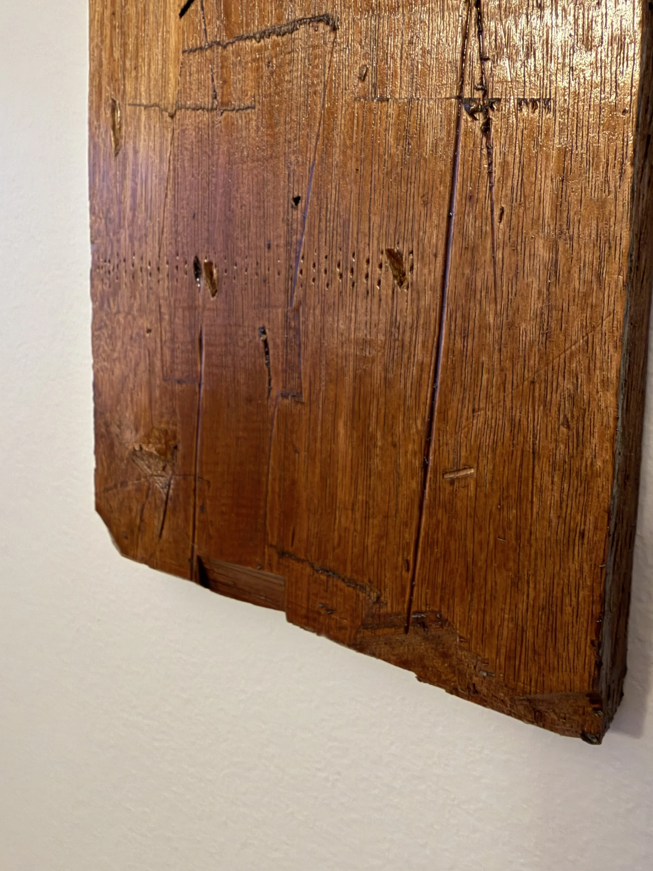 Close-up of a wooden picture frame corner hanging on a beige wall, with a partial view of artwork inside the frame.