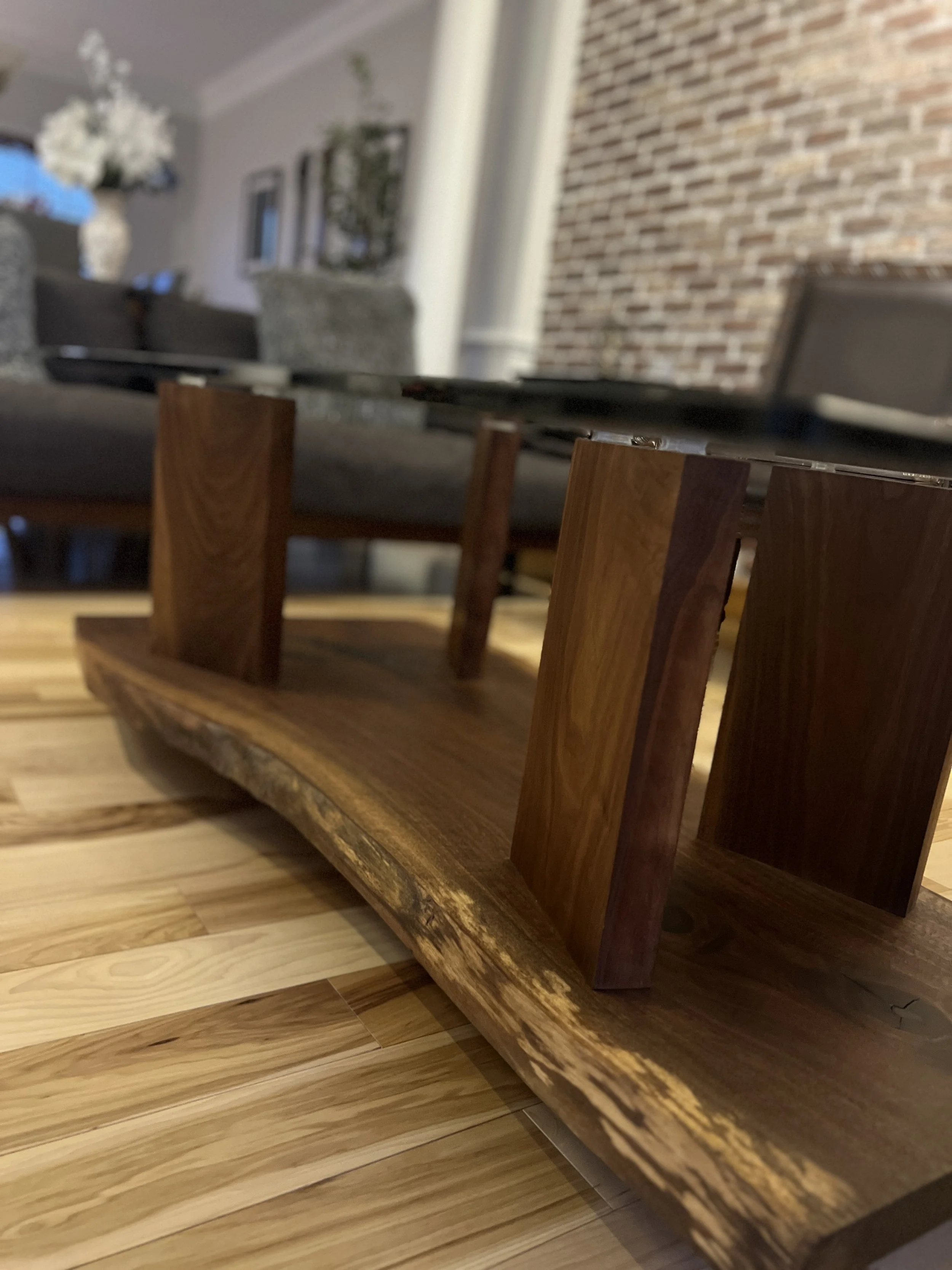 Close-up of a wooden origami horse on a wooden table with a blurred living room background.