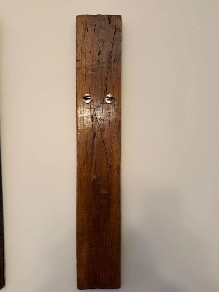 Close-up of a wooden picture frame mounted on a white wall, with a section of artwork visible inside the frame.