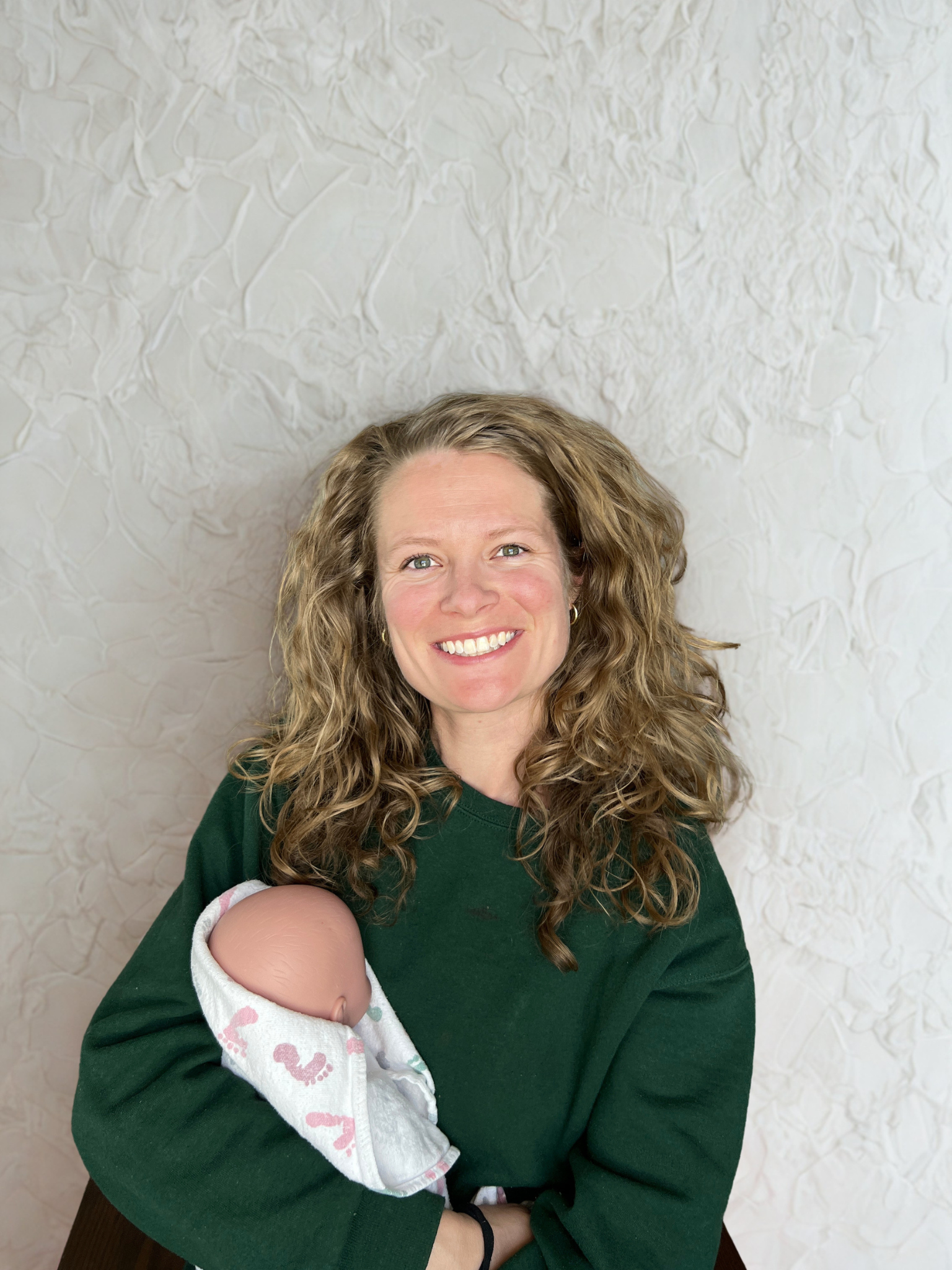 Kylie Pina RN, IBCLC smiling holding demo baby