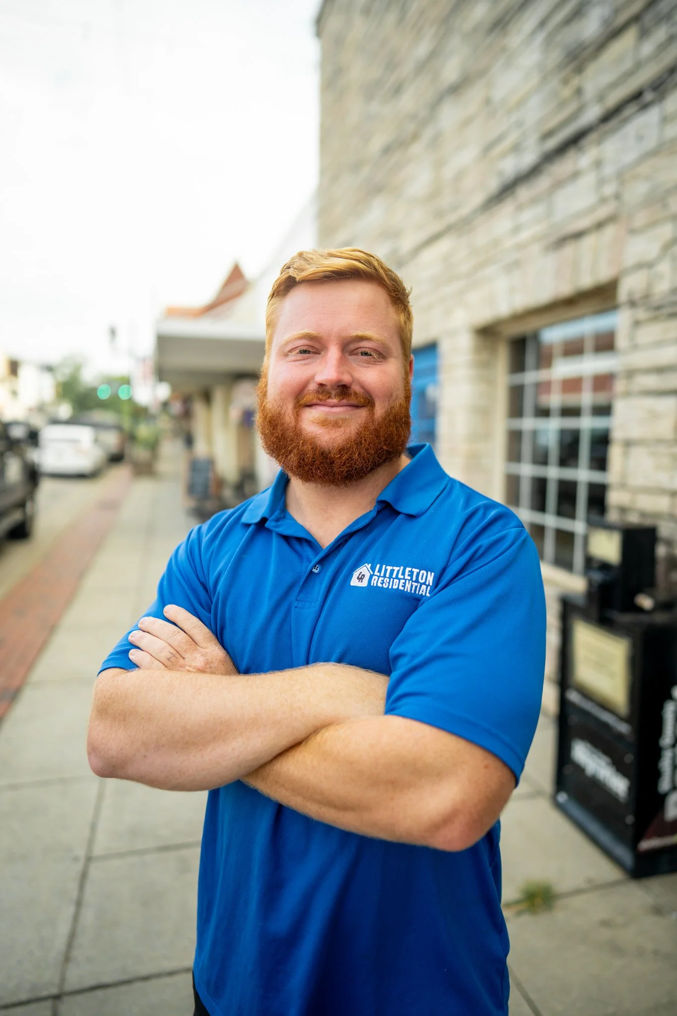 Smiling man with red hair and beard in white polo shirt