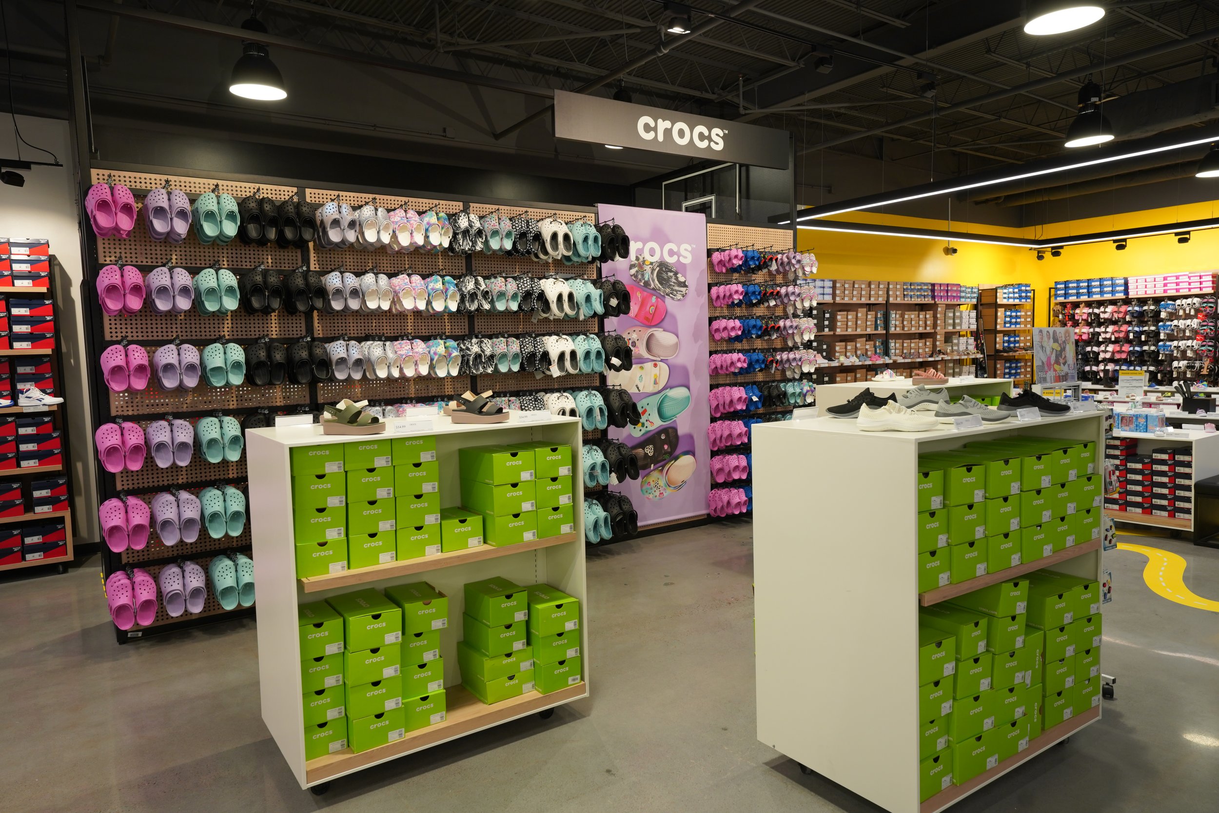 Display of colorful Crocs sandals on wall and on shelves in a shoe store.