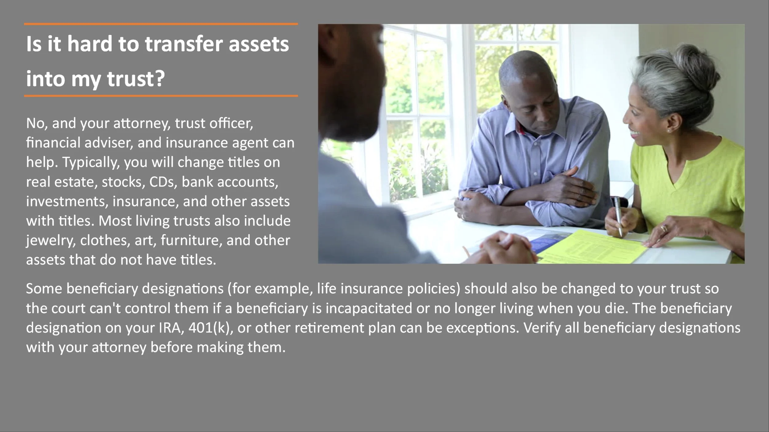 A woman with gray hair and a bright green top is sitting at a table, signing a document. Two men with dark skin are sitting across from her, one of whom is blurred out of the frame, in a well-lit room with large windows.