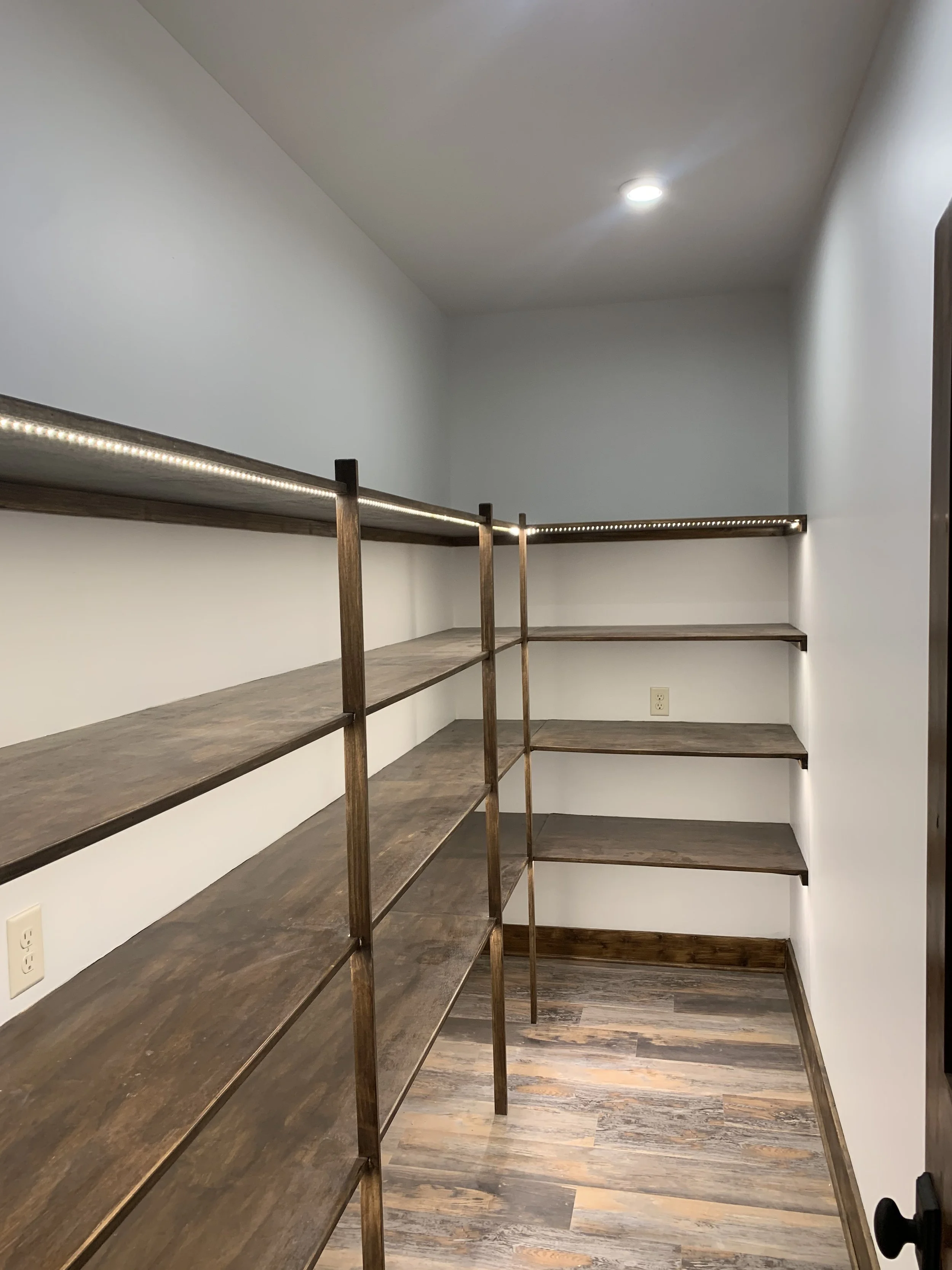 Empty pantry with wooden shelves and LED strip lighting