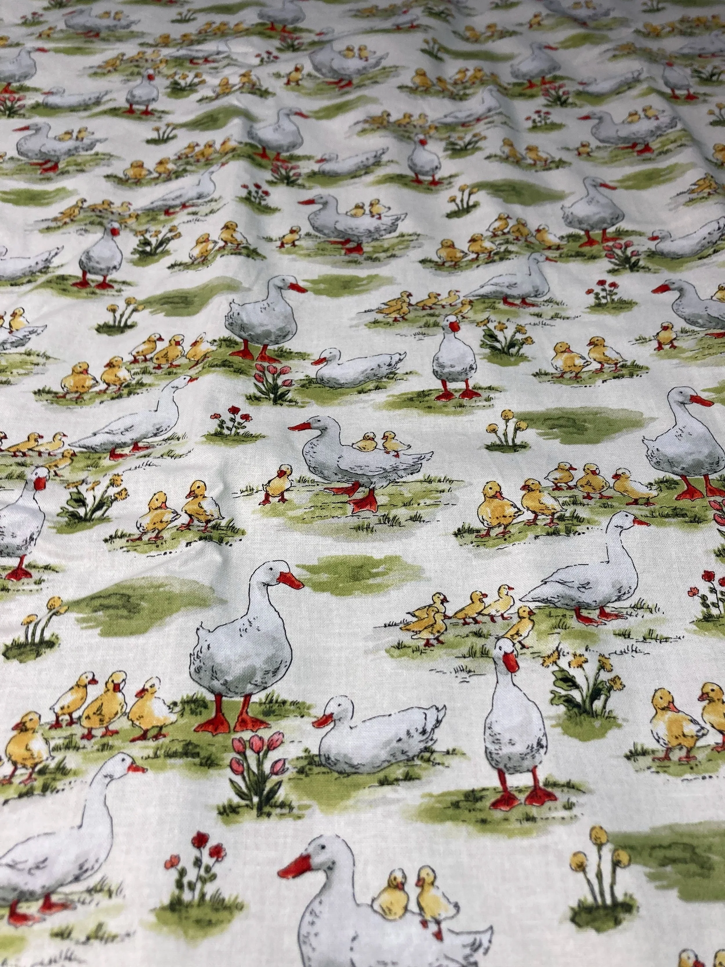 Detailed view of 100% cotton fabric with a vintage-inspired goose, gosling, and tulip pattern in soft greens and reds.