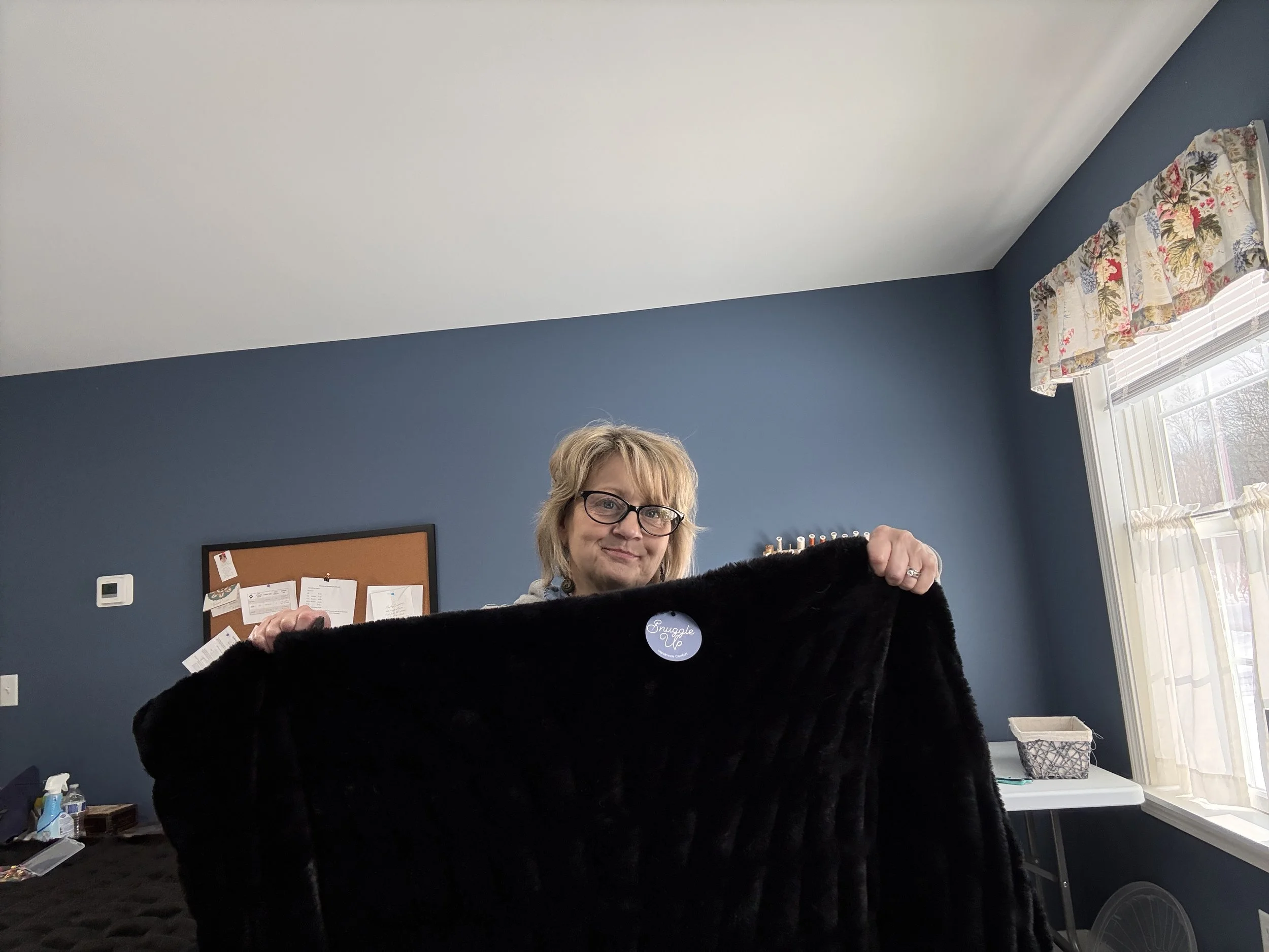 IMG_0268.jpegA woman holding up the large, double-sided black Midnight Mink blanket to show its impressive size and drape.