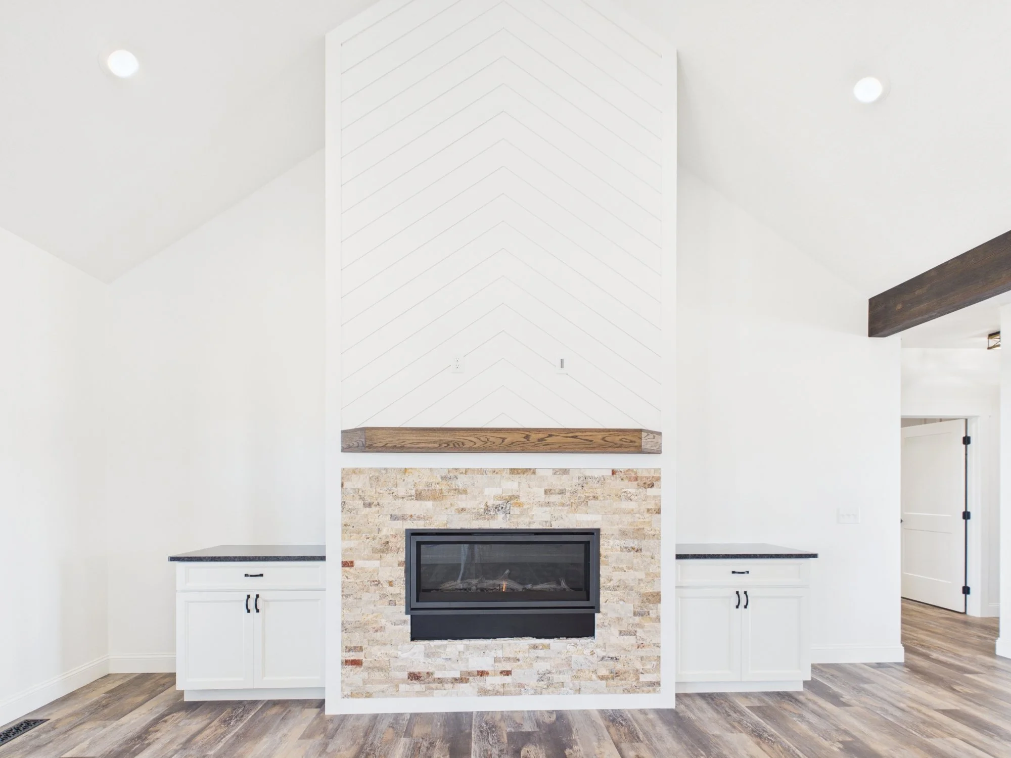 Modern living room interior with a white and brick fireplace, white cabinets, and wood flooring.