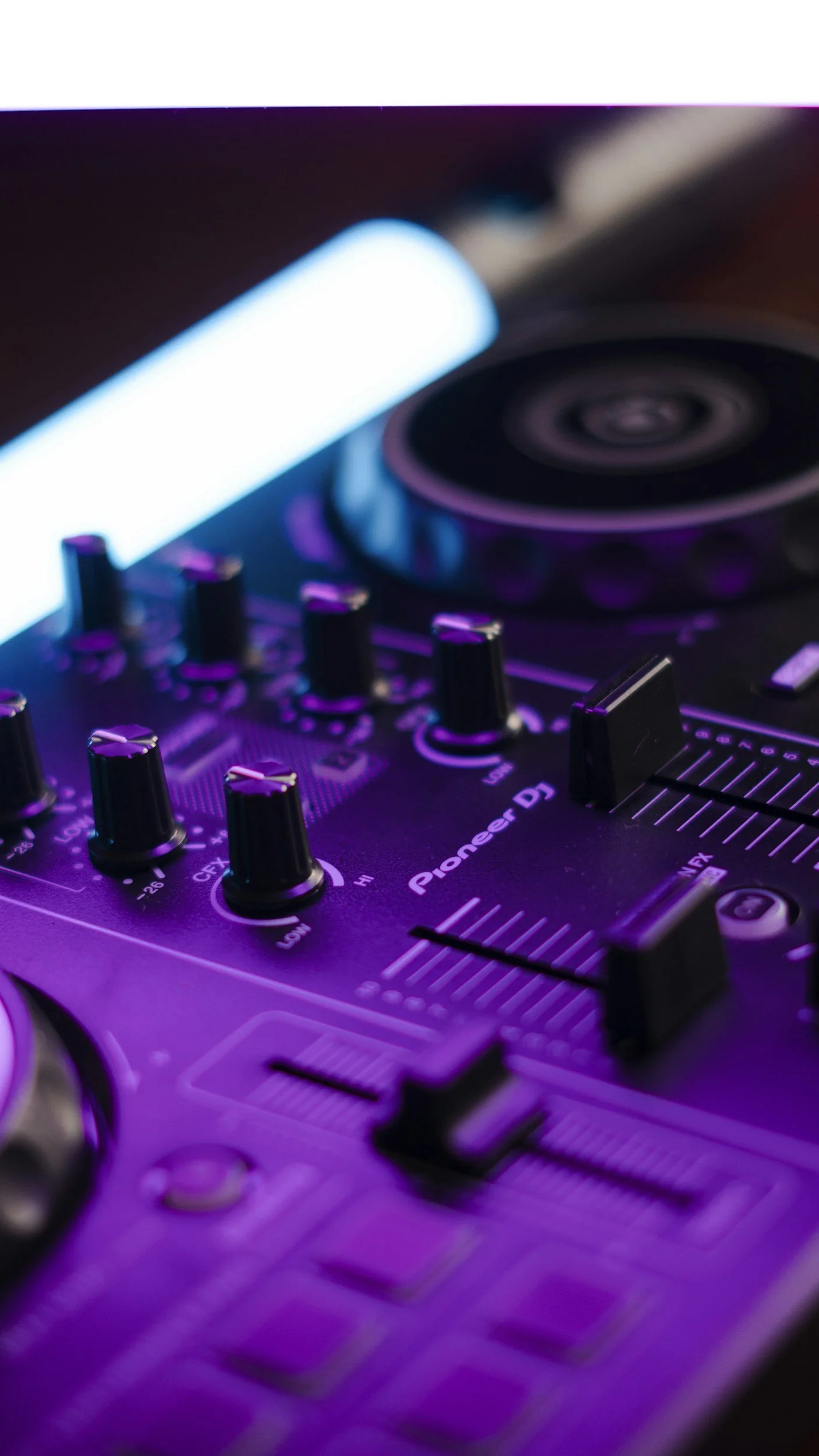 Close-up photo of Pioneer DJ controller with purple and blue lighting.