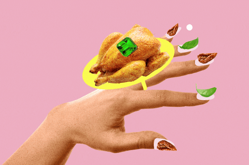 A hand with decorated nails holding a yellow dish with a cooked chicken, a green dice, and green leaves against a pink background.