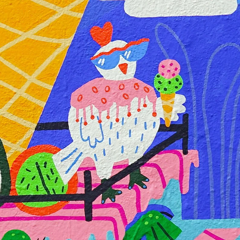 Colorful mural of a cartoon bird wearing sunglasses with a heart-shaped accessory on its head, sitting on a pink platform with an ice cream cone next to it, and a green clock and plant nearby, set against a vibrant background.