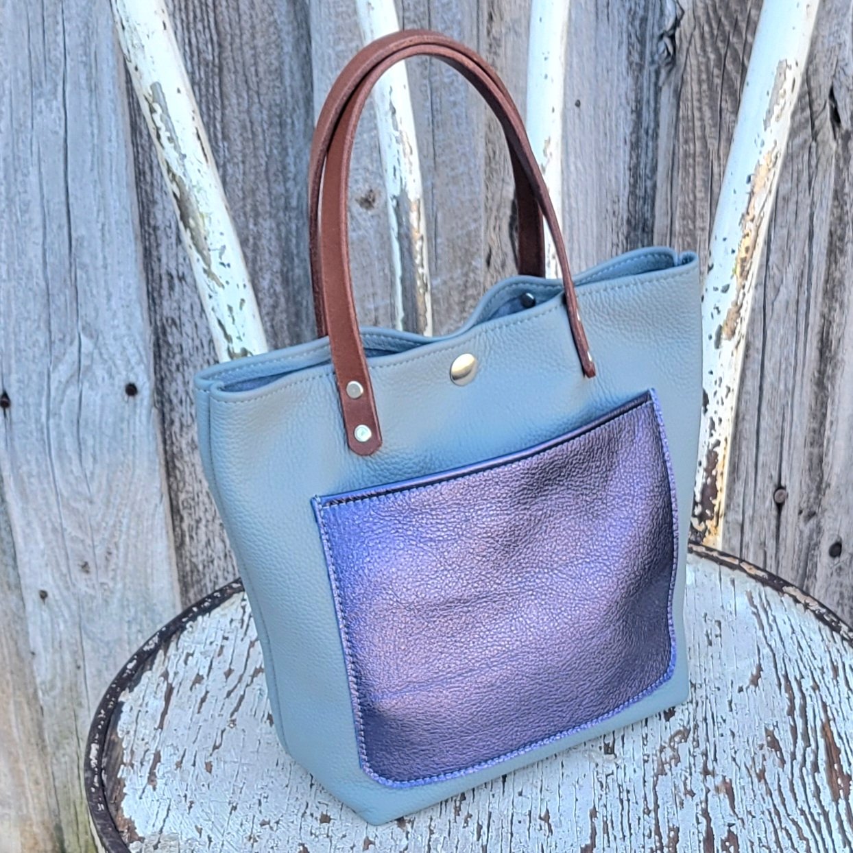 Pebble grain leather in silver combines smartly with a metallic sapphire pocket on this mini tote bag
