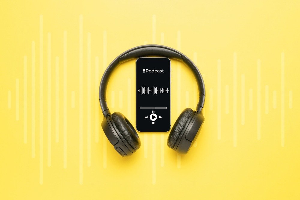 Casque audio entourant un smartphone affichant un podcast, sur fond jaune.