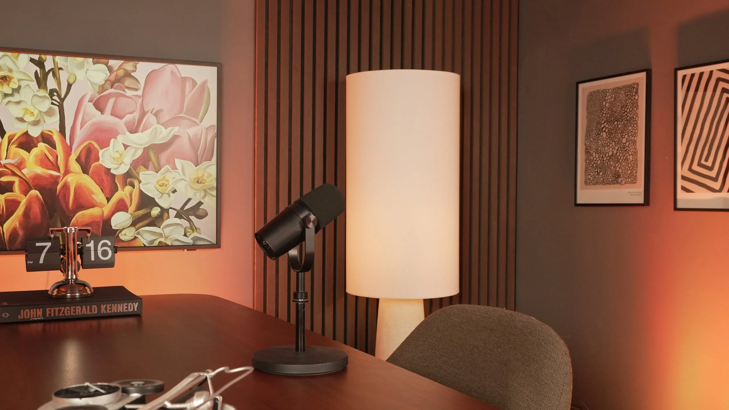 Deux hommes assis dans des fauteuils, discutant avec des microphones dans un studio moderne avec éclairage et plantes.