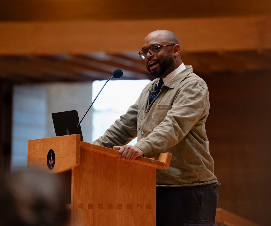 A speaker stands at a podium delivering a talk.