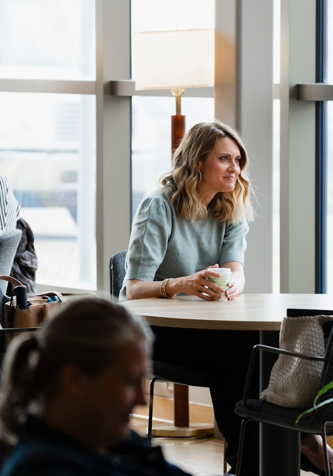 A smiling woman is listening to a conversation.