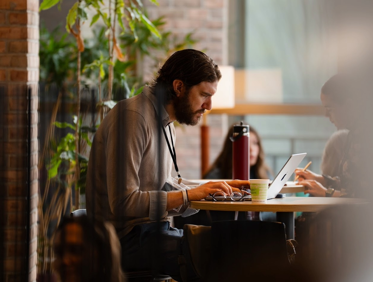 A seated man looks intently at his laptop.