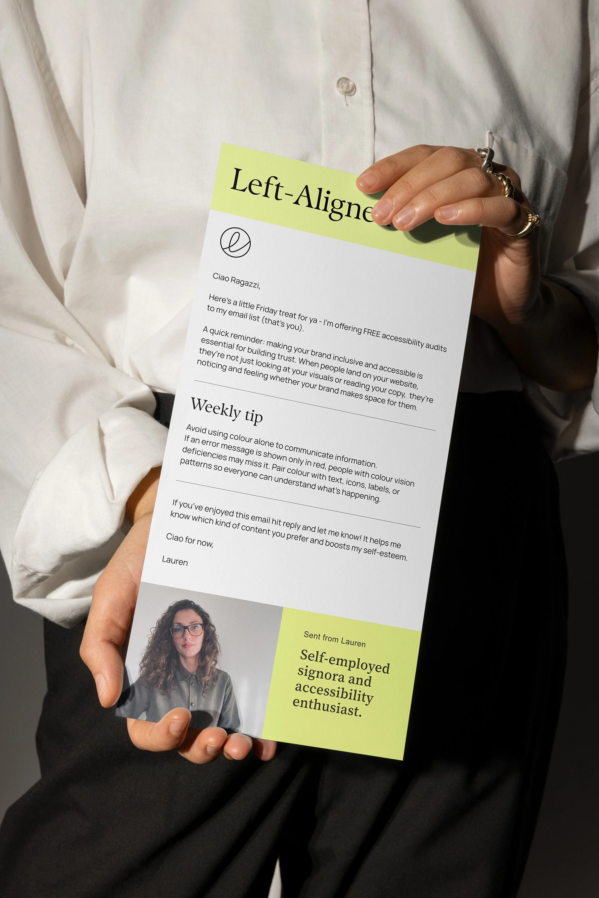 someone holding up a printed newsletter that says 'left aligned' at the top followed by with accessibility