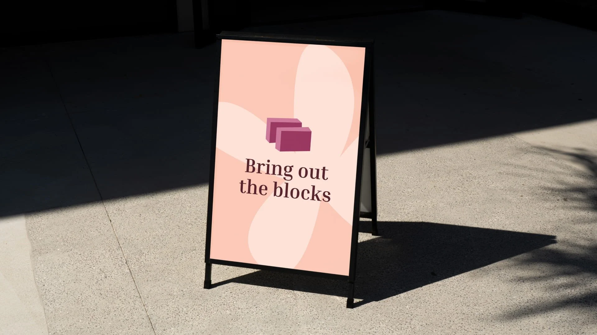 A mock up of an A frame board with a poster that says 'bring out the blocks' and an illustration of yoga blocks