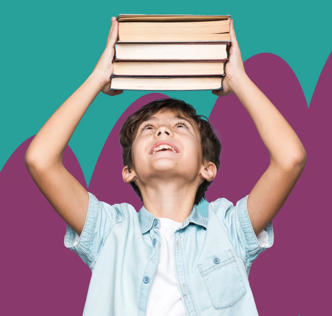 A young boy holding a stack of books above his head