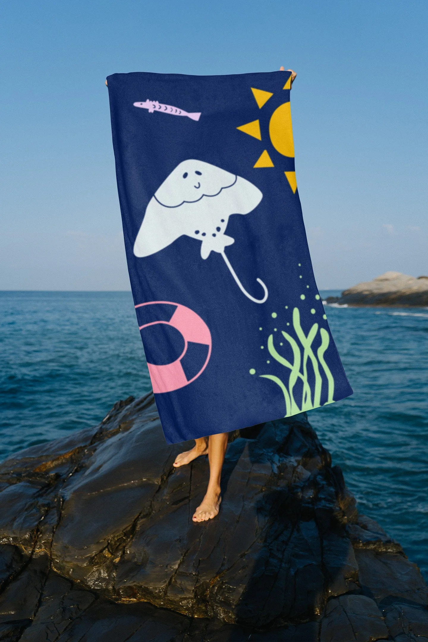 Someone standing on rocks holding up a branded towel in front of them
