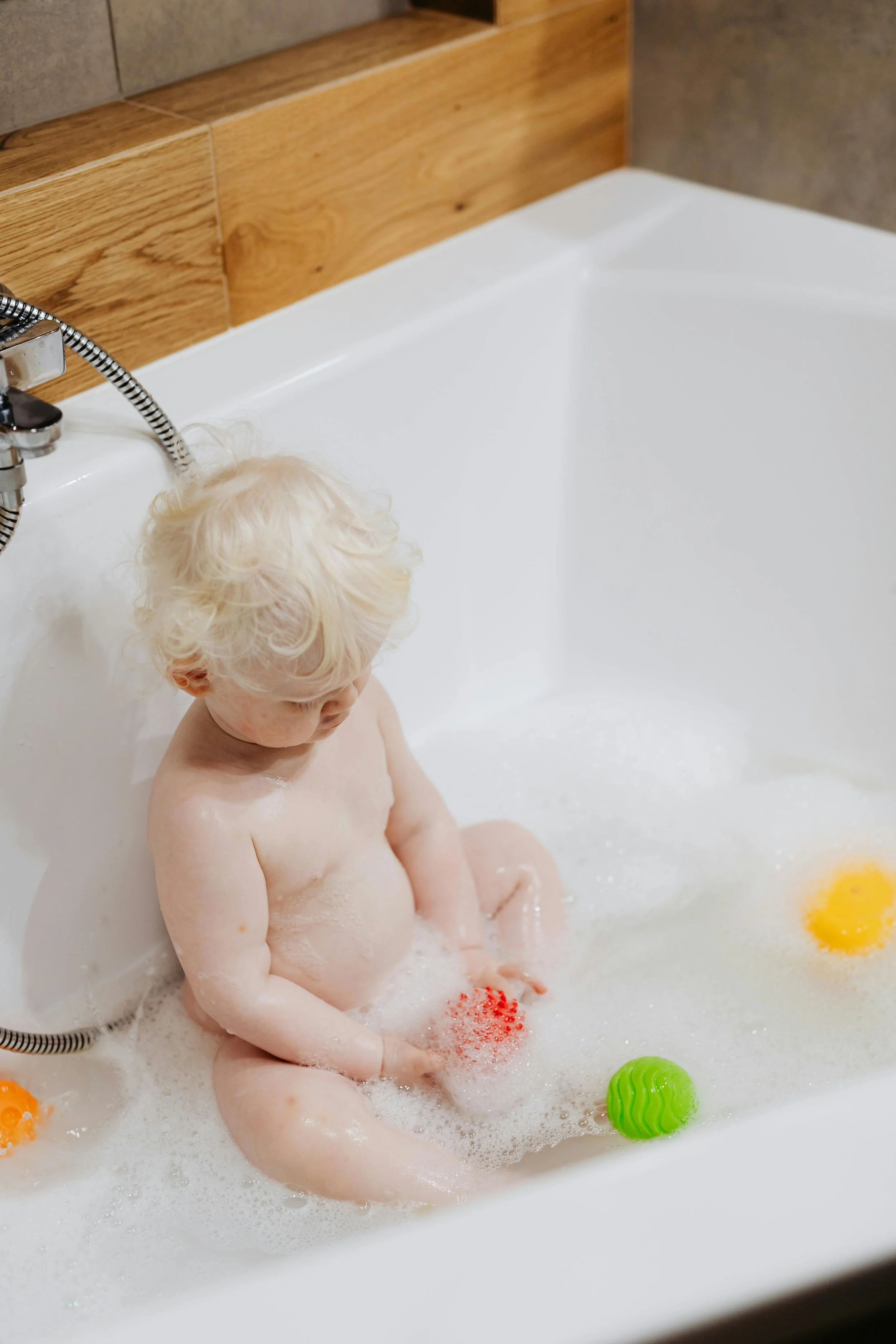 Baby in a bathtub playing with bath toys