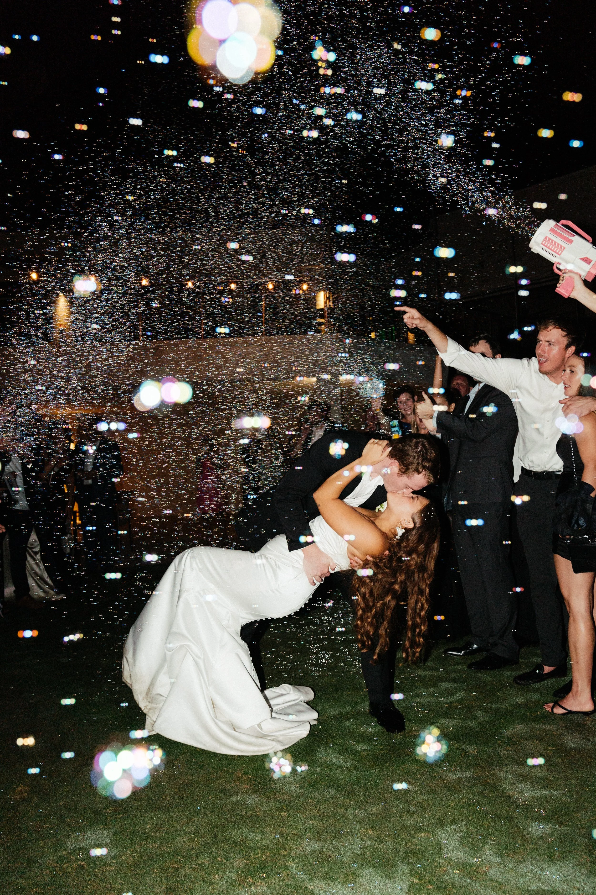 Groom dipping bride at sendoff with bubbles
