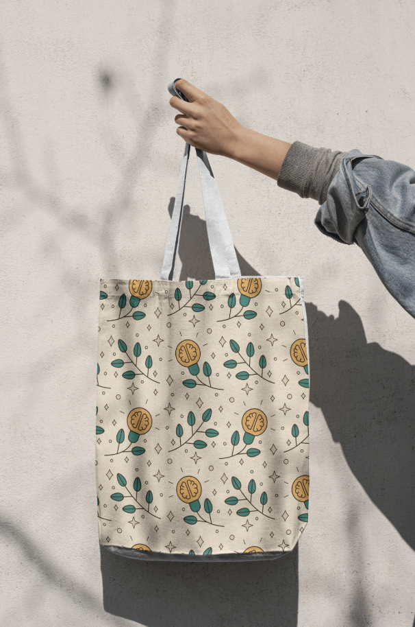 A person holding a tote bag with a floral pattern against a plain wall.