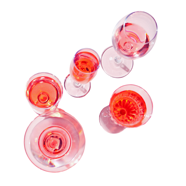Cinque bicchieri di vino rosa visti dall'alto, disposti in cerchio su uno sfondo nero.