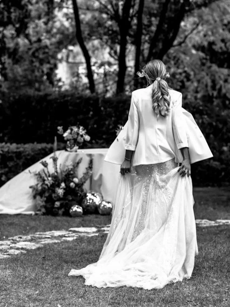 Donna in abito da sposa in un giardino con decorazioni floreali e una tavola apparecchiata.
