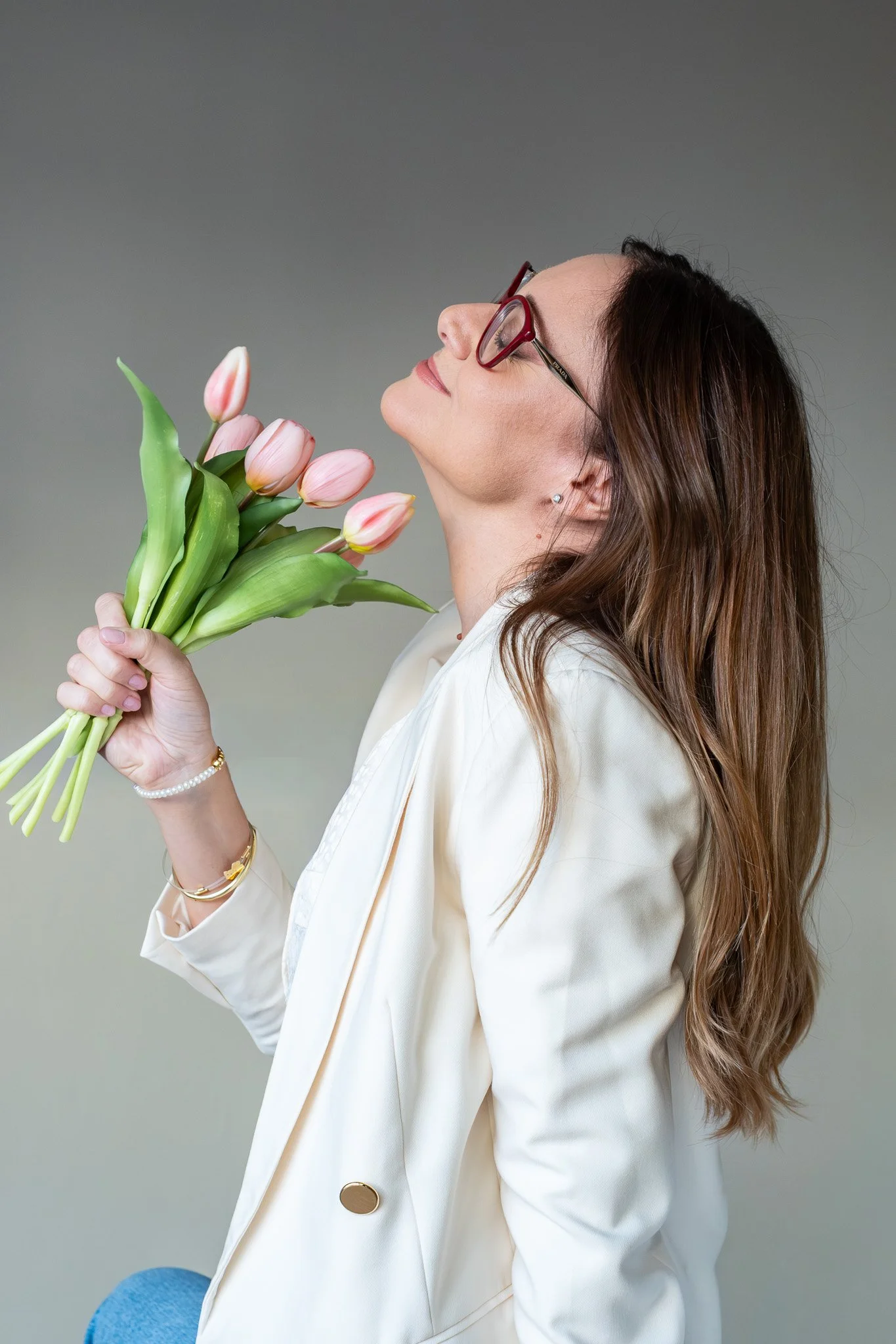 foto di donna con tulipani rosa in mano sognante ma elegante con blazer panna e rifiniture oro
