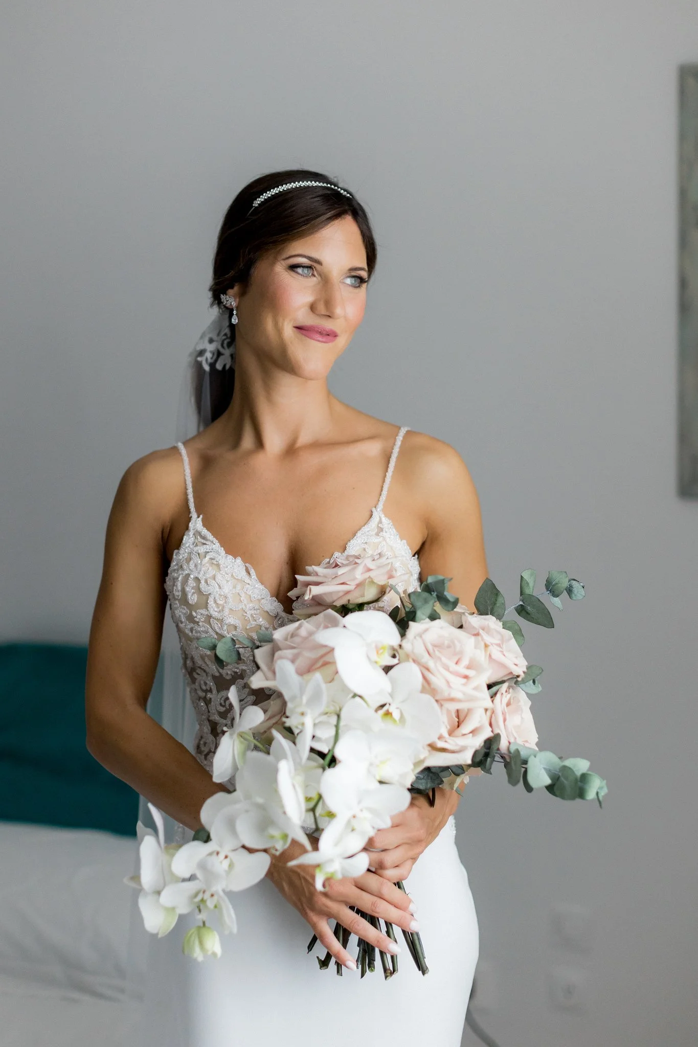 Una donna in abito da sposa tiene un grande bouquet di fiori bianchi e rosa