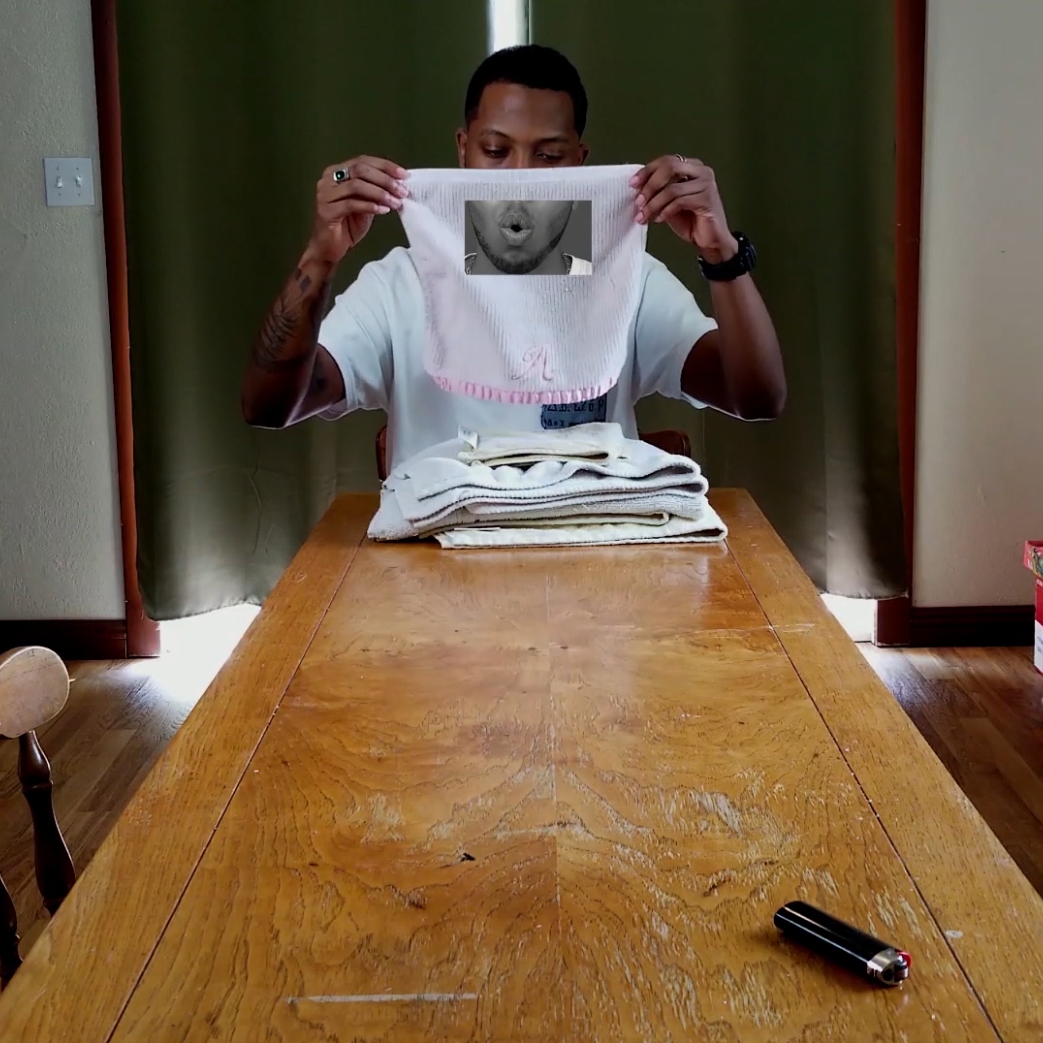A man sits at the end of a table holding up a washcloth