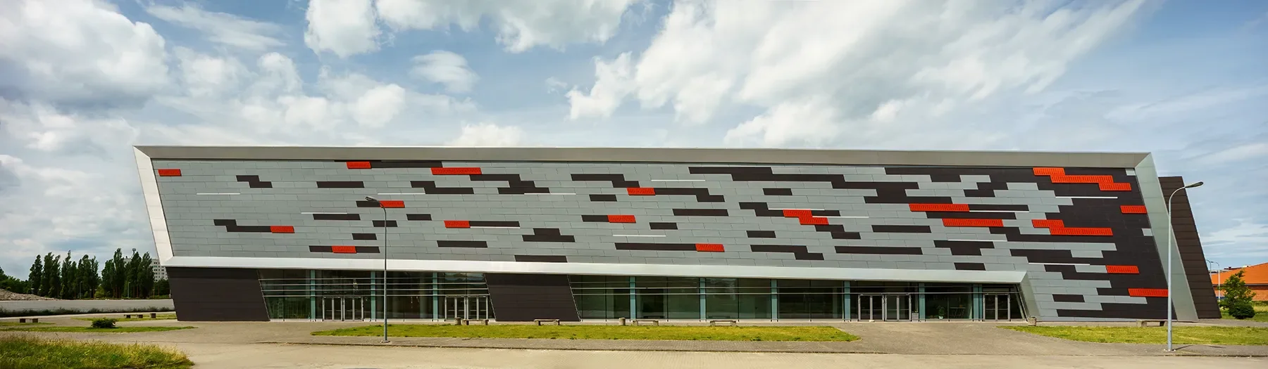 Wide side view of the Koszalin Sports and Entertainment Arena with angular metal facade and horizontal lines
