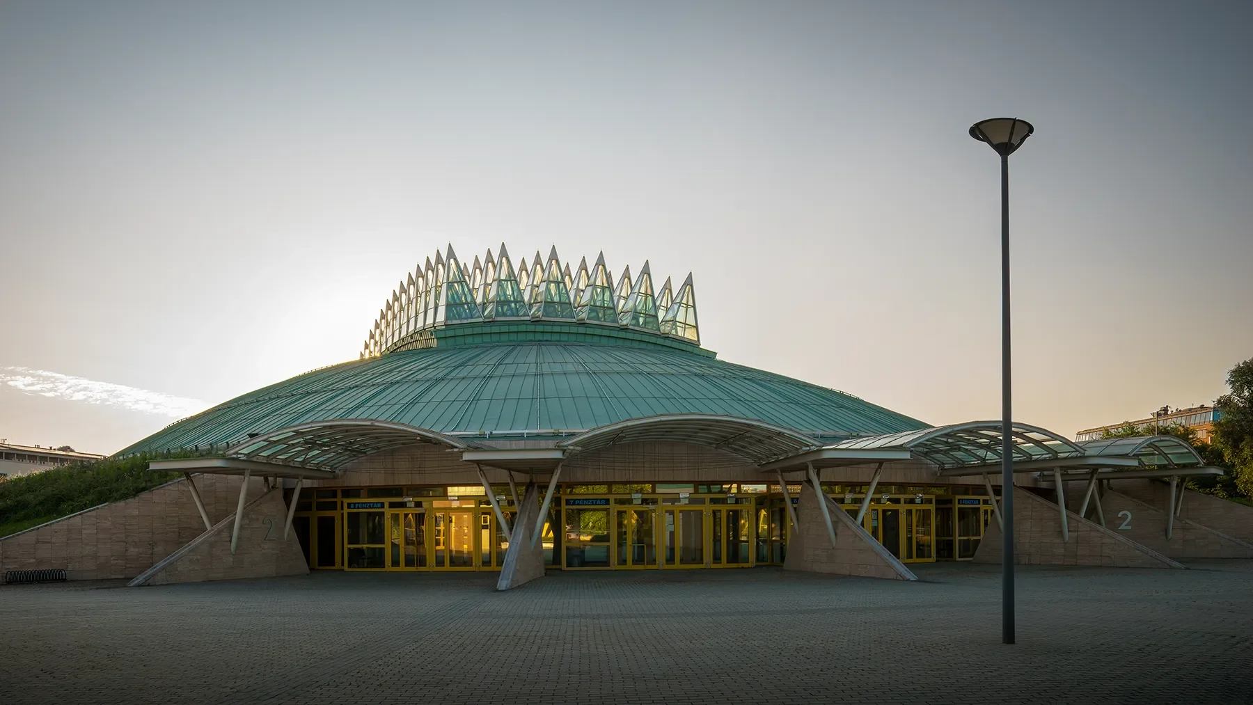 Back entrance of Tüskecsarnok sports and events hall in Budapest, early morning shadow with backlit roof spikes