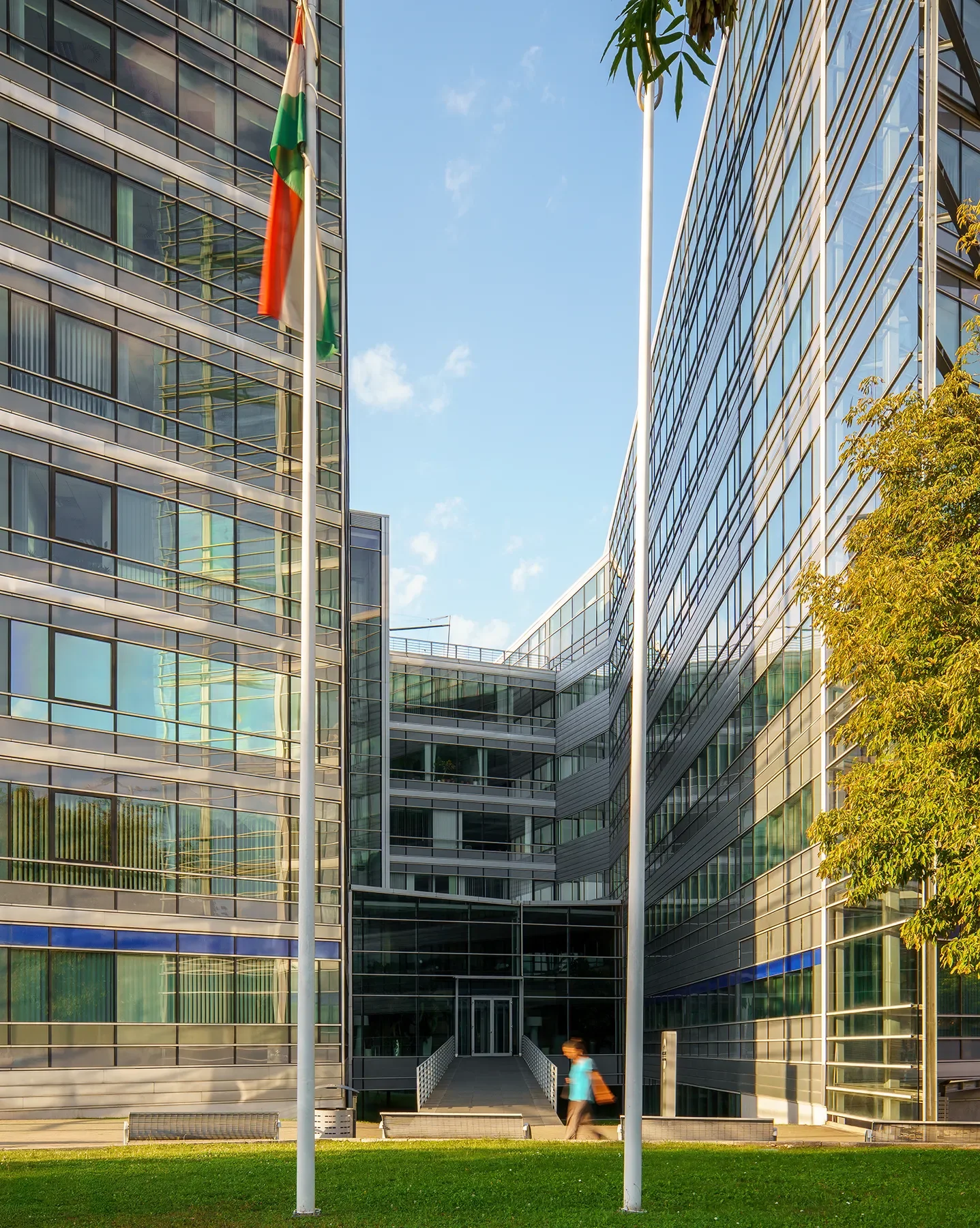 Front entrance of Alkotás Point Office Budapest with glass reflections, bridge, and flags
