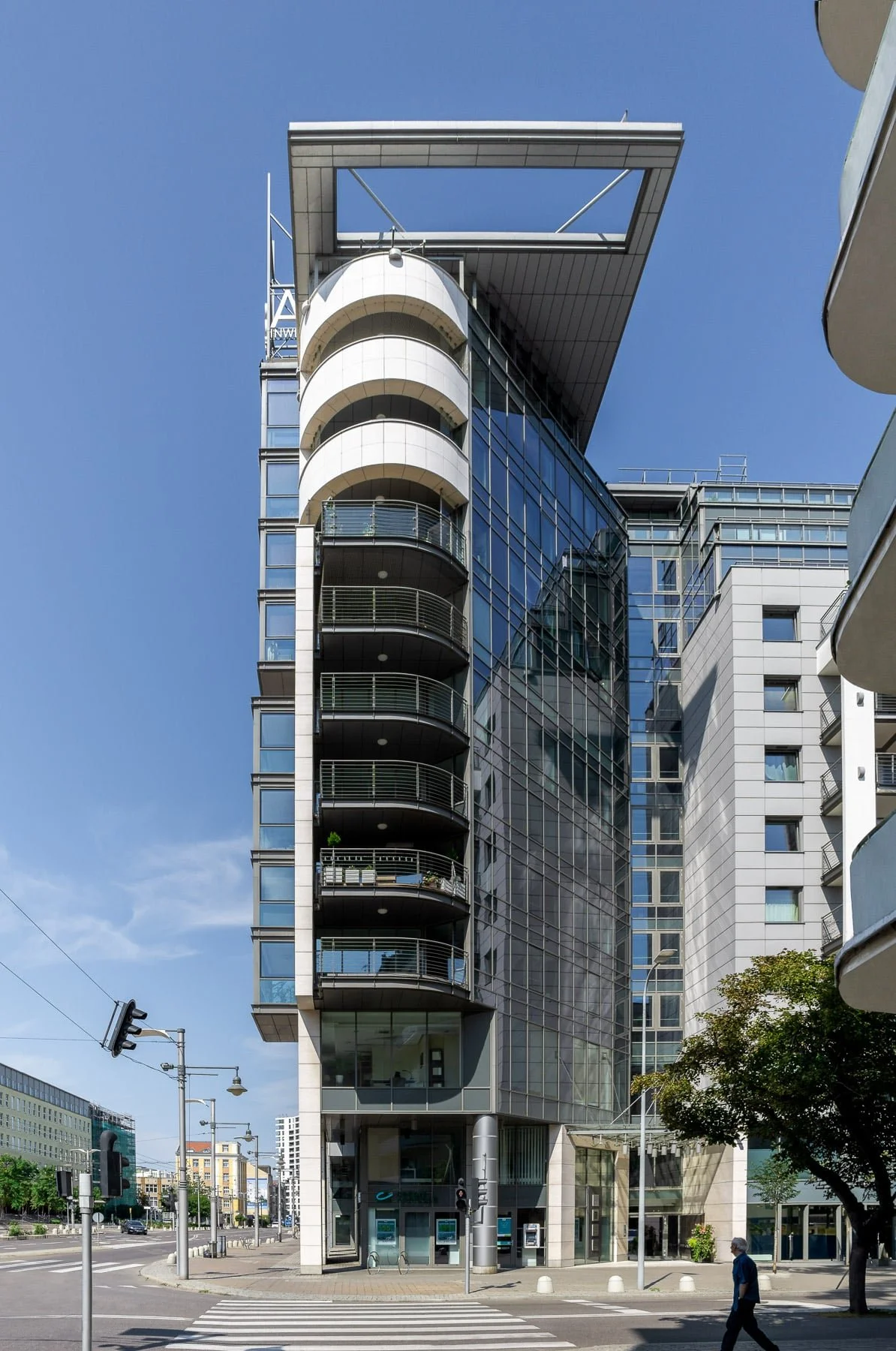 Gdynia, Poland: Contemporary Transatlantyk building with a striking, curved facade, featuring repeating balcony elements and a large glass section. A person walks in the foreground, adding scale.